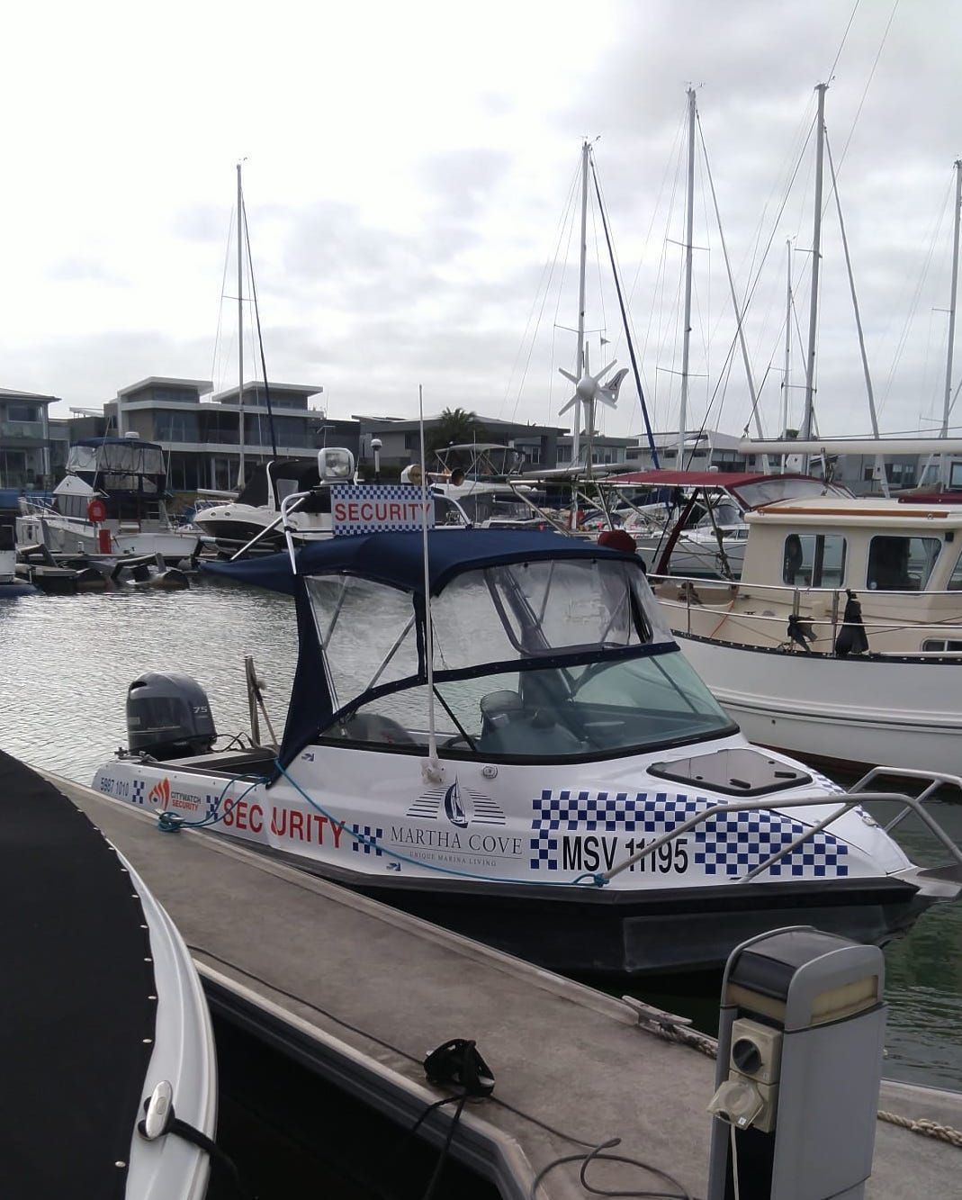 Security boat docked at a marina. White hull with blue and red graphics, a 