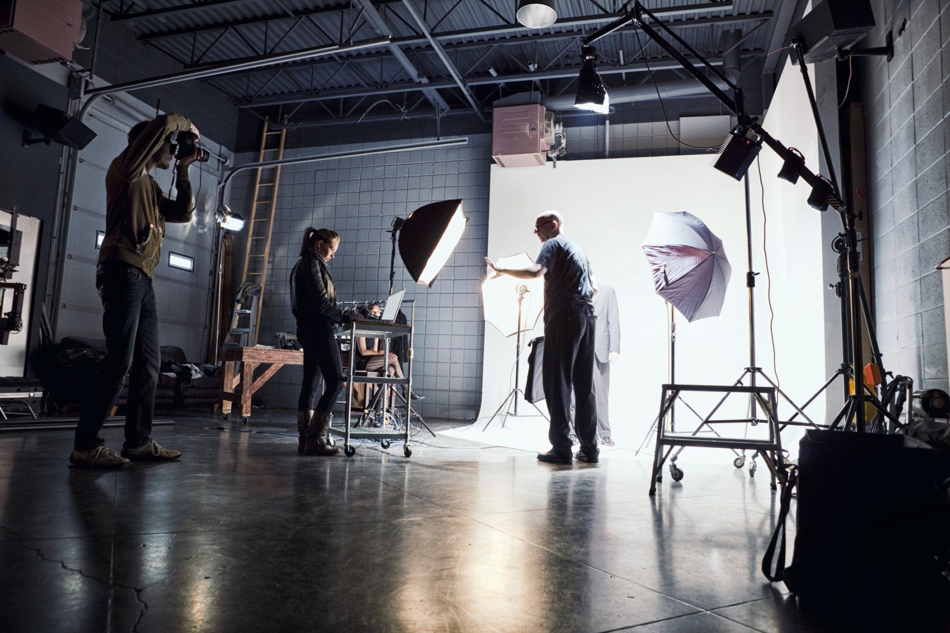 Photographers setting up studio lighting for a shoot, white background, people working indoors.
