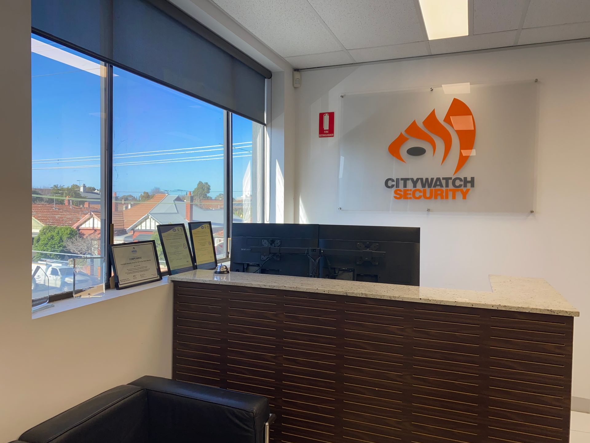 Reception area with Citywatch Security logo. Window view, desk, and awards.